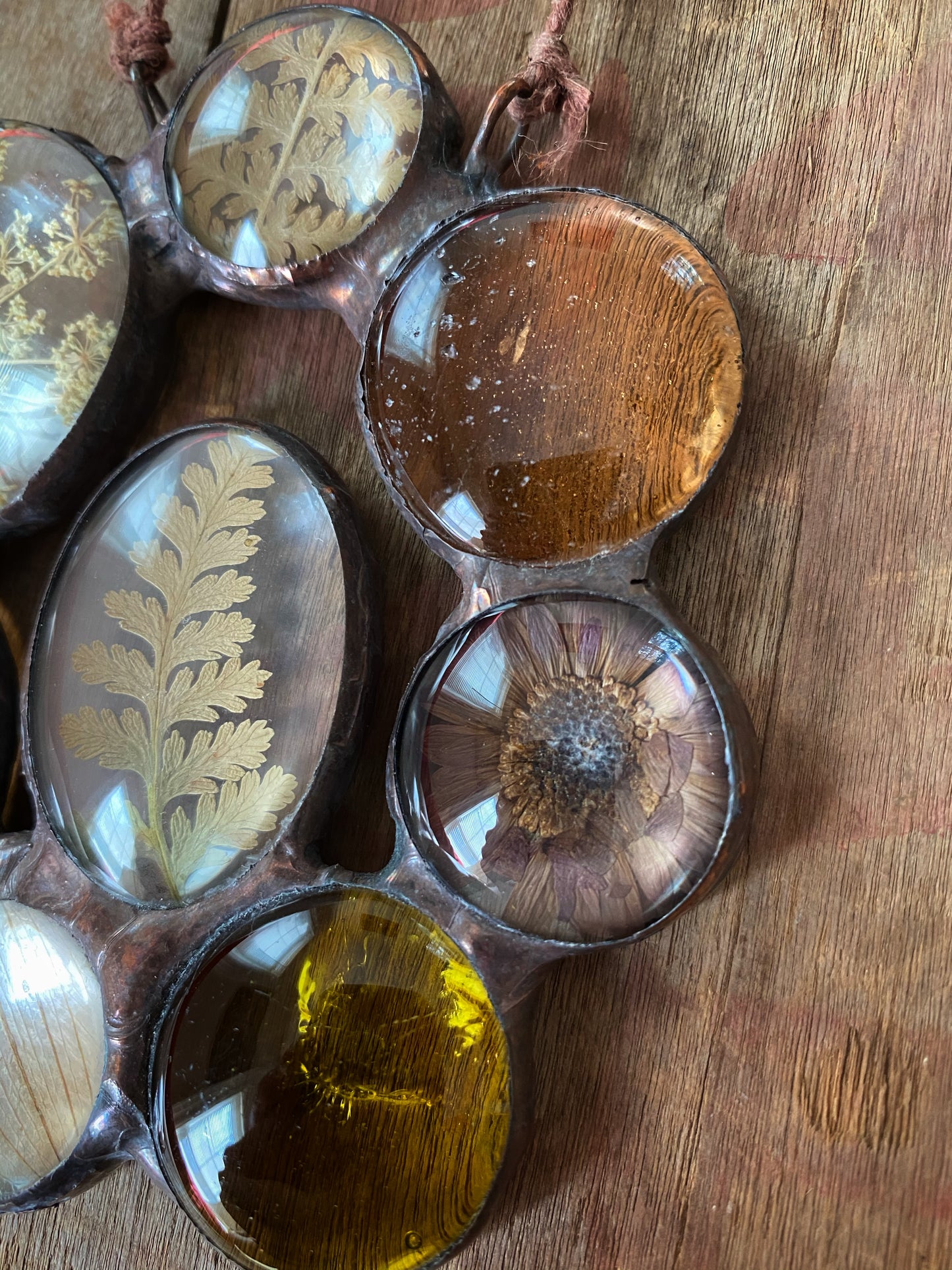 Decorative glass art with natural elements flowers ferns on a wooden surface.
