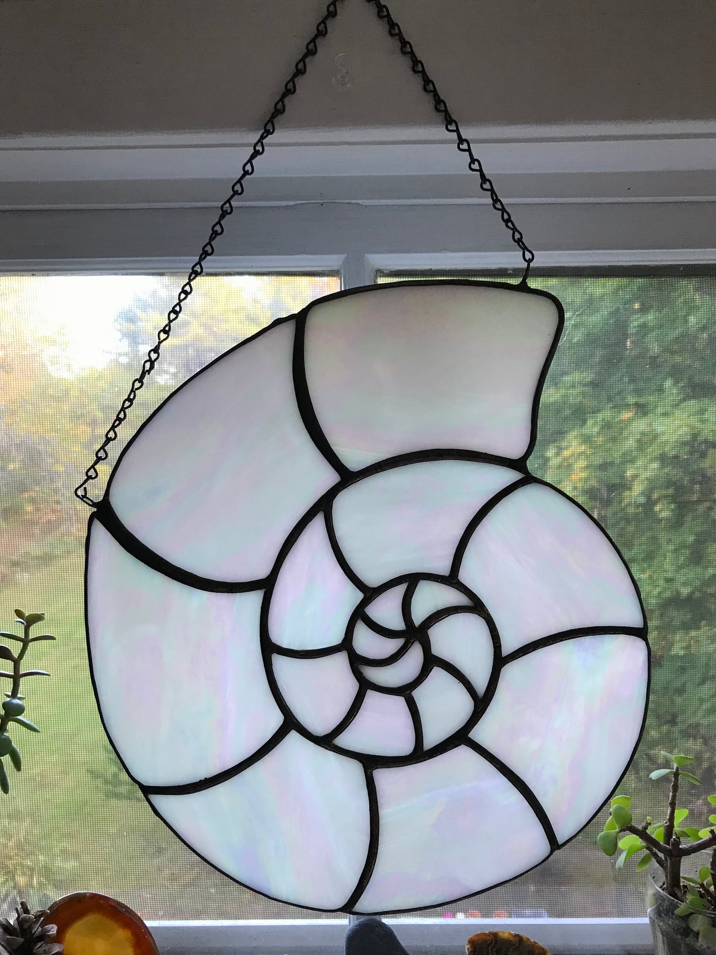 Stained glass shell decoration hanging on a window.