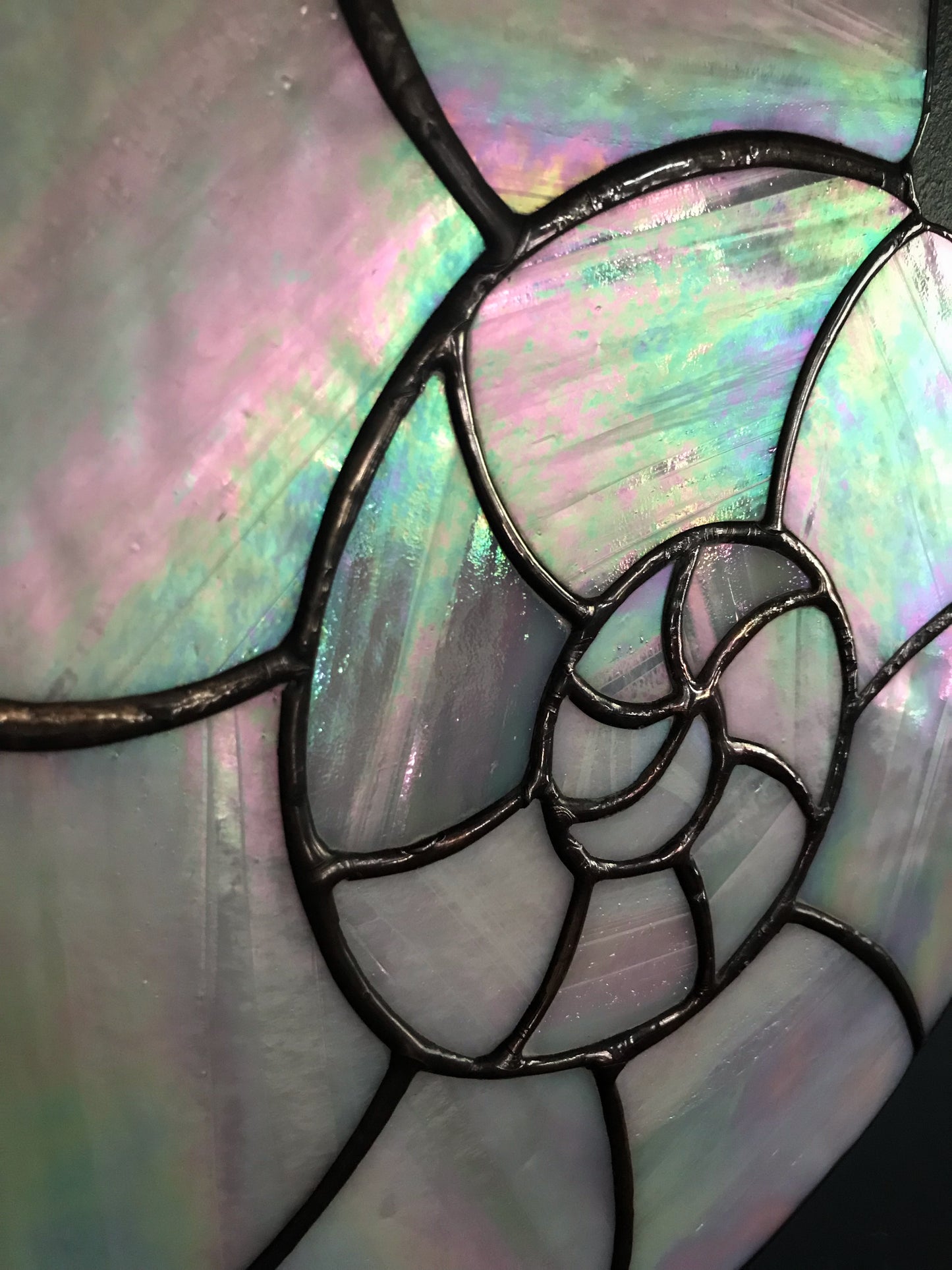 Close-up of a stained glass panel with iridescent colors and black lead lines.