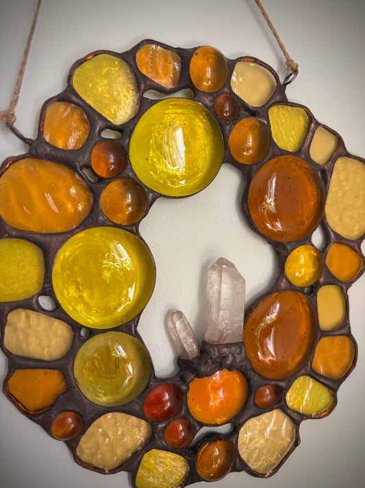 Decorative stained glass with colored glass beads and quartz crystals in the center on a white background.