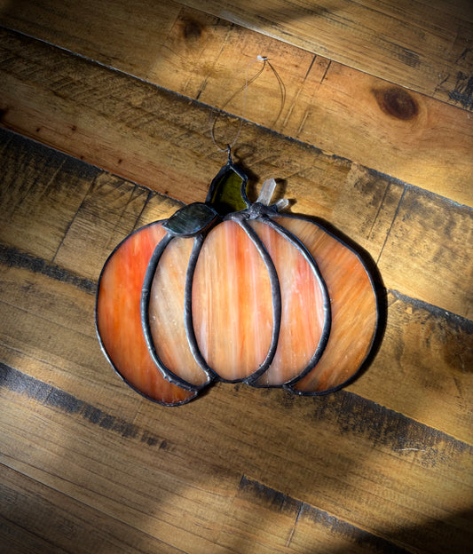 Decorative glass pumpkin on a wooden surface.